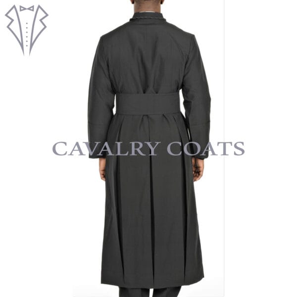 A black Anglican clergy robe cassock with a matching cincture belt. The robe is long-sleeved and floor-length, featuring traditional button-up closure and a standing collar. The cincture belt is tied around the waist, completing the clerical attire.